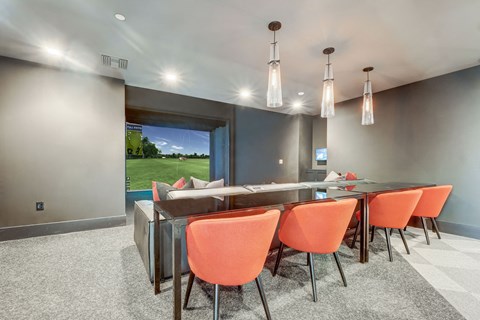 A conference room with orange chairs and a view of a green field outside the window.